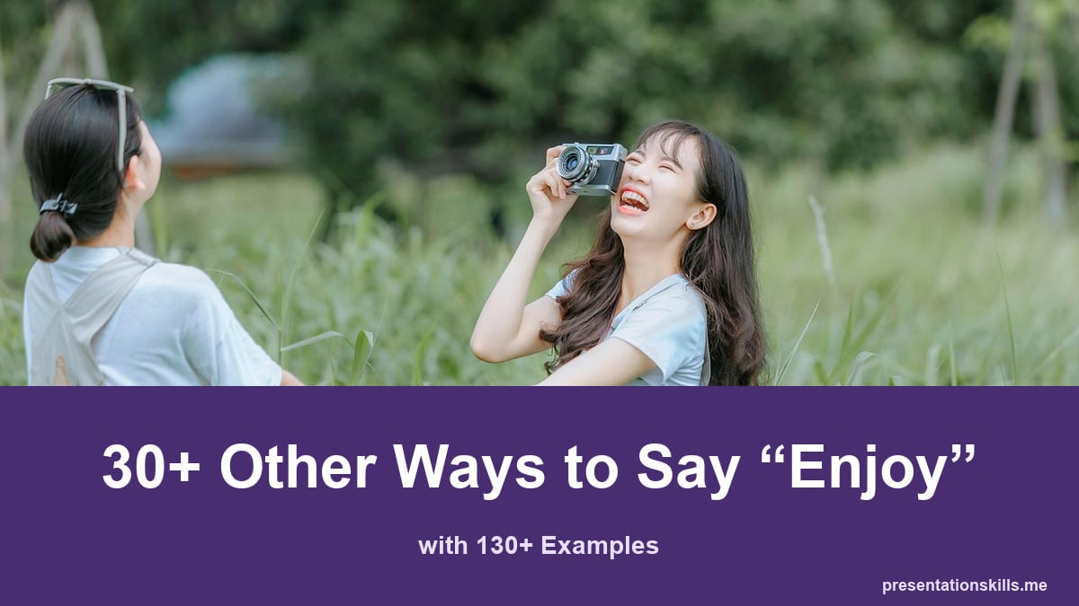 30+ other ways to say enjoy, with 130+ examples; Two friends laugh outdoors while holding hands and taking a photograph.